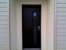 Porte d'entrée en alu noir sur maison en bois